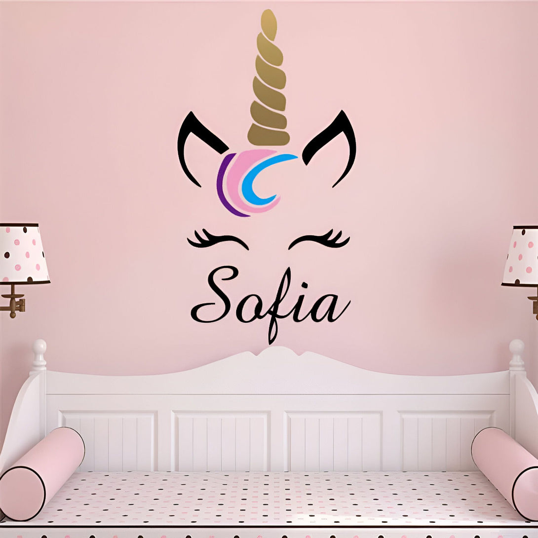 Chambre d'enfant rose avec un lit blanc et une décoration murale d'une tête de licorne noire, dorée, rose et bleue, avec le prénom "Sofia" écrit en noir en dessous. Deux lampes à pois roses et marron encadrent le lit., 45501134209279 | Licorne Shop