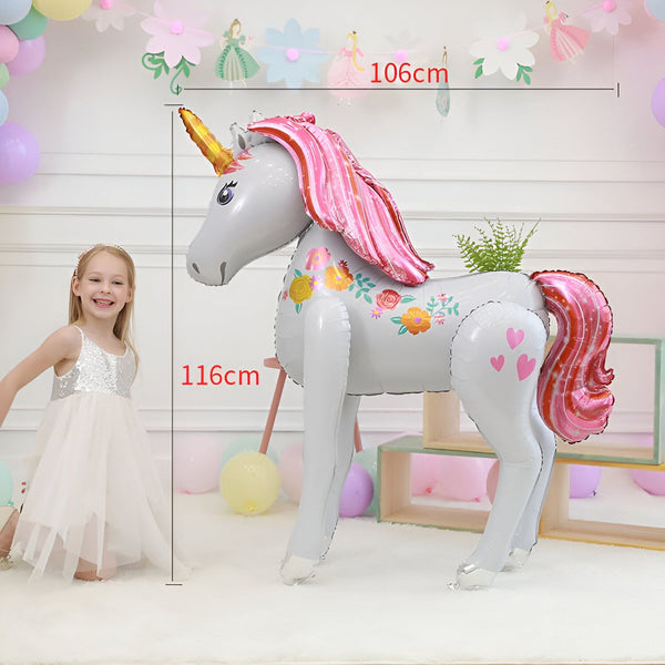 Ballon géant licorne grise et rose, décoré de fleurs et de cœurs, avec une petite fille souriante en robe blanche à paillettes. Dimensions indiquées. Idéal pour une fête d'anniversaire féérique., 45501108093183 | Licorne Shop