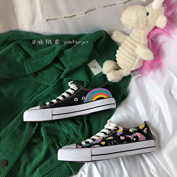 Deux paires de baskets noires à motifs arc-en-ciel et licorne sur un fond blanc avec une veste verte et une peluche d'licorne. Chaussures à lacets blanches et semelles épaisses. Style décontracté et mignon., 45502280433919,45502280466687,45502280499455,45502280532223,45502280564991,45502280597759,45502280630527,45502280663295,45502280696063 | Licorne Shop
