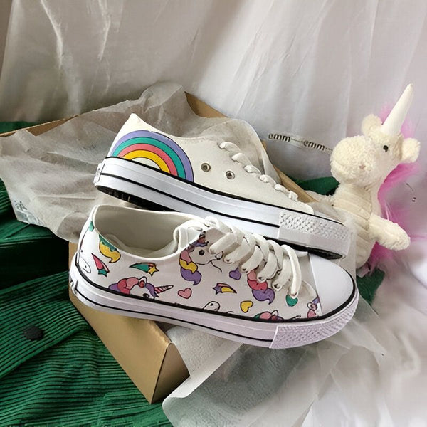 Deux jolies baskets blanches avec des motifs : une avec un arc-en-ciel et l'autre avec des licornes. Un petit jouet licorne se trouve à côté des chaussures, dans une boîte en carton., 45502282858751,45502282891519,45502282924287,45502282957055,45502282989823,45502283022591,45502283055359,45502283088127,45502283120895 | Licorne Shop