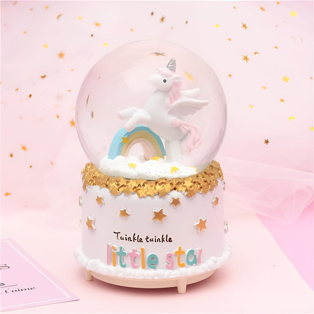 Boule à neige décorative avec un licorne ailé sur un arc-en-ciel, posée sur un socle blanc orné d'étoiles dorées et portant l'inscription "Twinkle twinkle little star". Idéal pour une chambre d'enfant., 45501134012671 | Licorne Shop