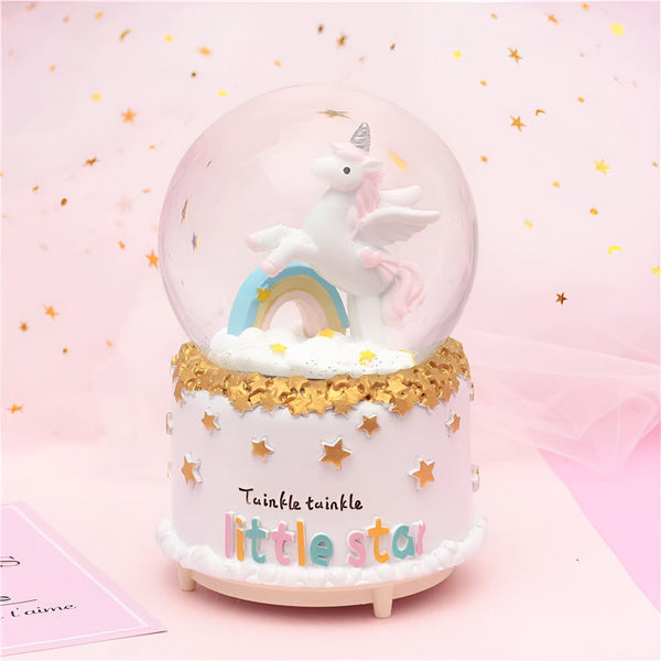 Boule à neige décorative avec un licorne ailé sur un arc-en-ciel, posée sur un socle blanc orné d'étoiles dorées et portant l'inscription "Twinkle twinkle little star". Idéal pour une chambre d'enfant., 45501134012671 | Licorne Shop