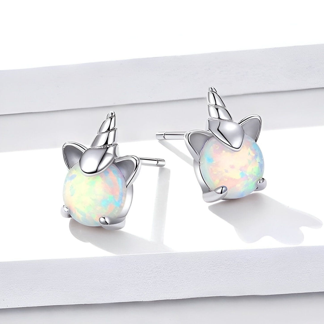 Une paire de boucles d'oreilles en forme de licorne en argent avec des pierres précieuses blanches.