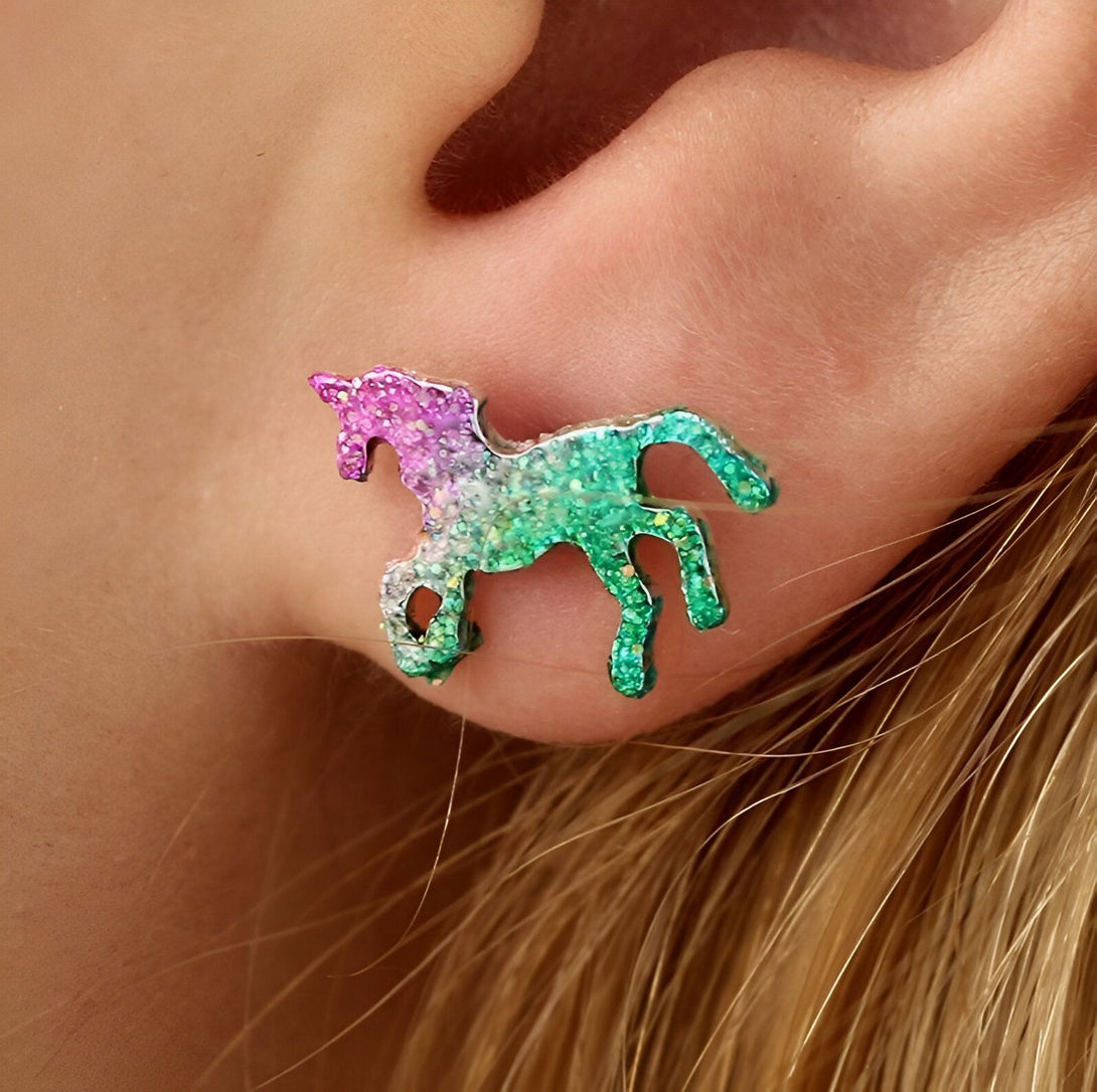 Une boucle d'oreille en forme de licorne avec des paillettes roses, vertes et bleues.