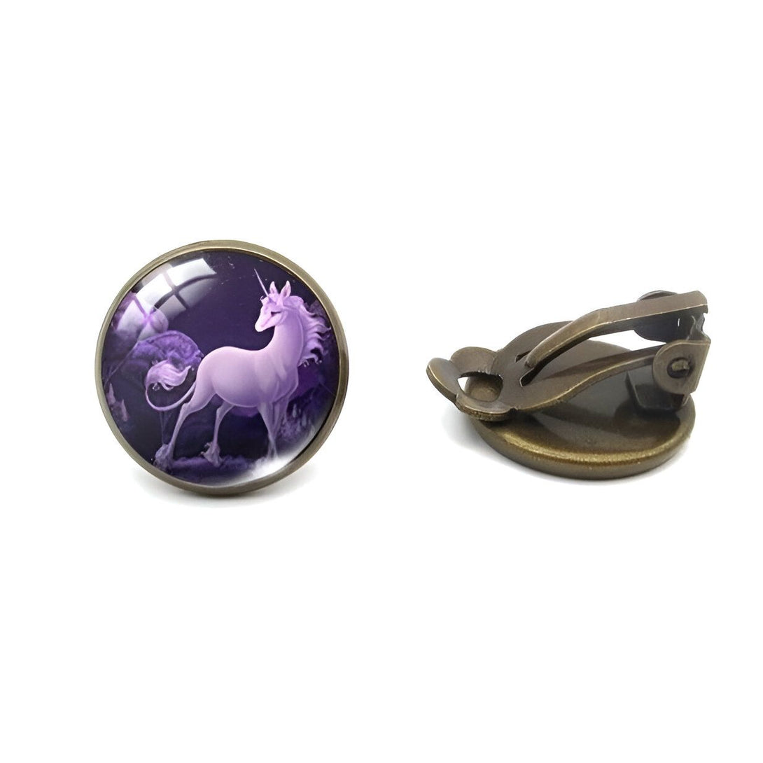 Une paire de boucles d'oreilles en bronze avec un cabochon en verre rond représentant une licorne violette sur un fond violet foncé.