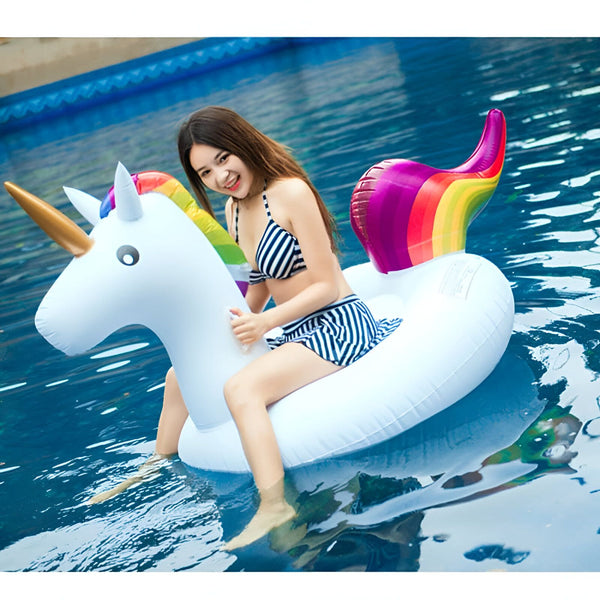 Une femme souriante en maillot de bain à rayures sur une bouée licorne gonflable colorée dans une piscine., 45501246177535 | Licorne Shop