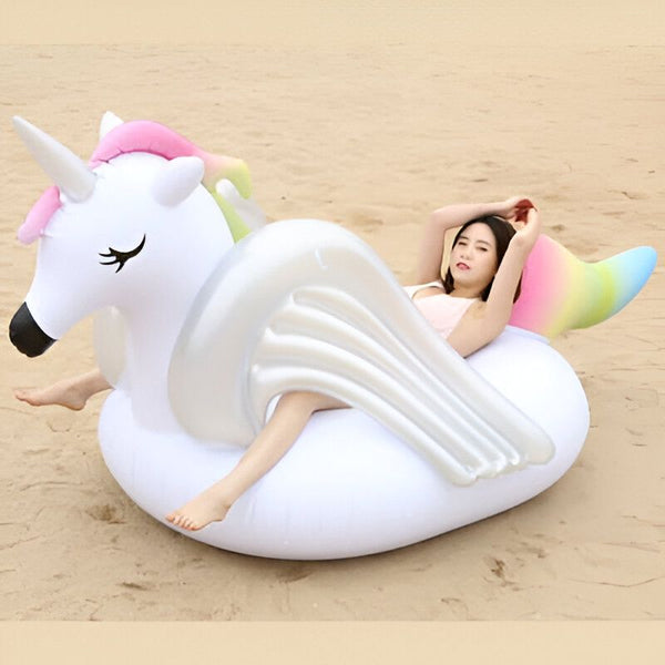 Femme se relaxant sur une bouée licorne gonflable blanche et colorée à la plage. Amusement estival et détente au soleil., 45501227335935 | Licorne Shop
