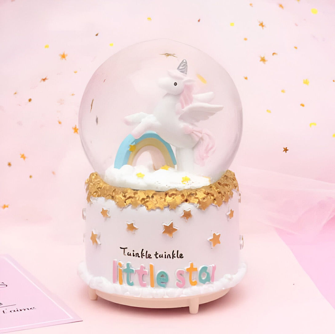 Boule à neige licorne avec l'inscription "Twinkle Twinkle Little Star" sur sa base. La boule contient une figurine de licorne blanche avec un arc-en-ciel. Fond rose avec des étoiles dorées. Cadeau pour enfant, décoration féerique, collection de boules à neige., 45501133717759 | Licorne Shop