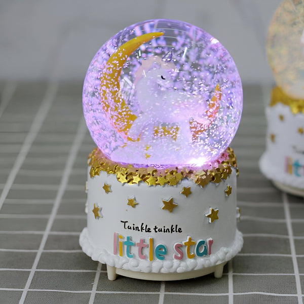Boule à neige musicale avec licorne et lune dorée. La base blanche décorée d'étoiles dorées porte l'inscription "Twinkle twinkle little star". Éclairage intérieur violet. Décoration féérique pour chambre d'enfant., 45501133553919 | Licorne Shop