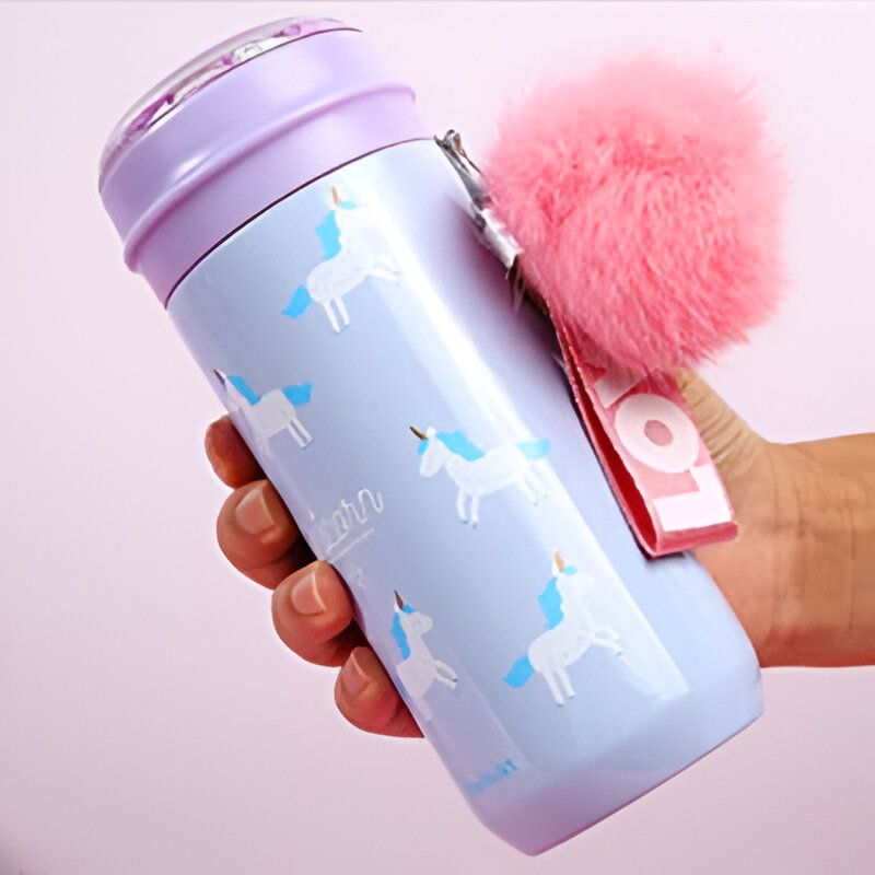 Bouteille d'eau pastel avec des motifs de licornes et un pompon rose. Couvercle violet et sangle de transport blanche et rouge. Main tenant la bouteille., 45501177069823 | Licorne Shop