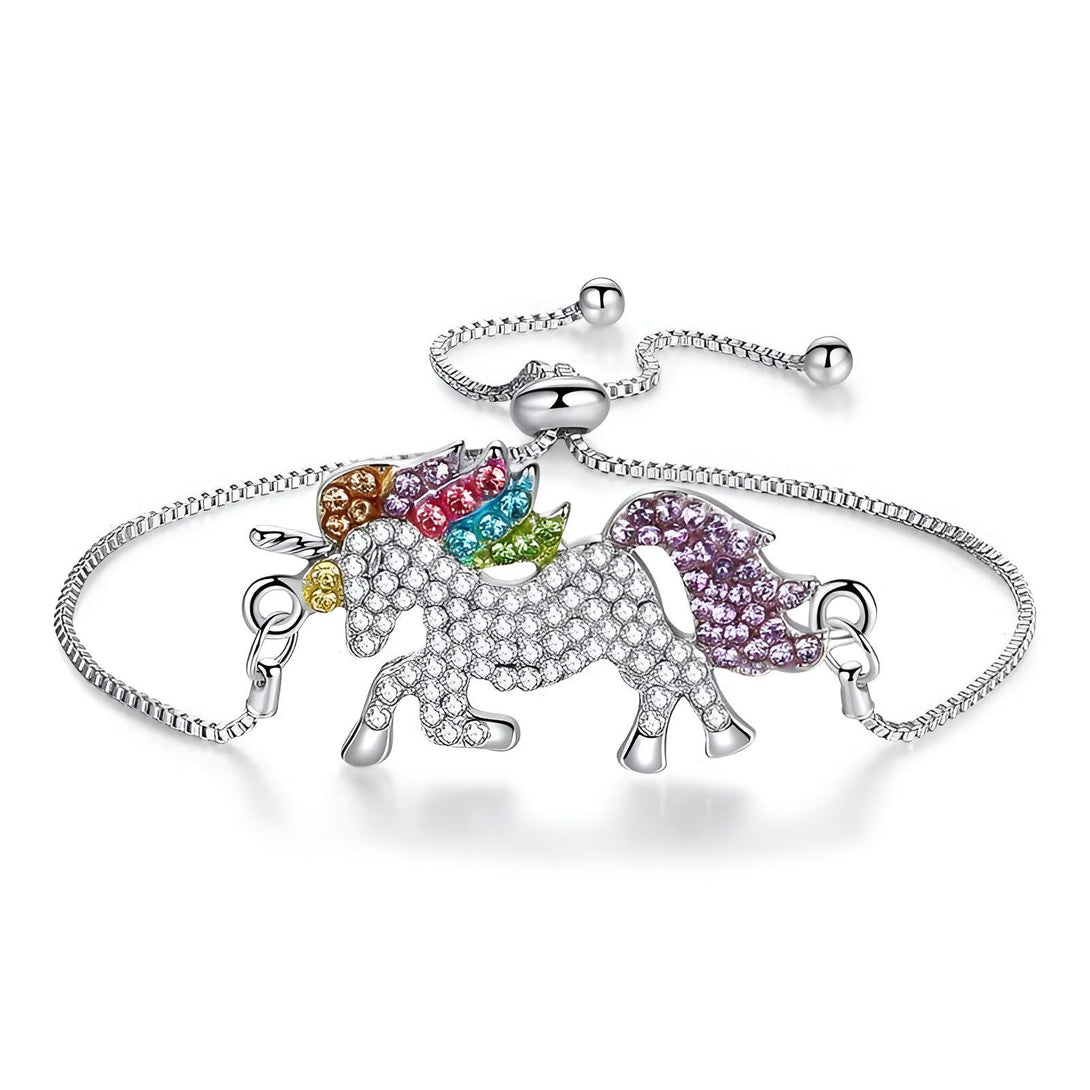 L'image représente un bracelet en argent avec un pendentif licorne. La licorne est sertie de cristaux de différentes couleurs. Le bracelet est réglable grâce à une chaîne d'extension.