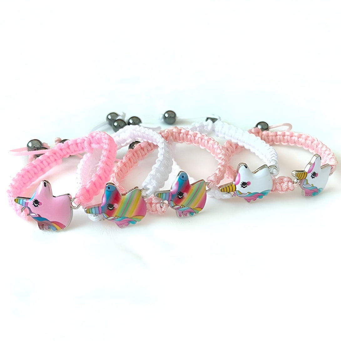 Quatre bracelets en corde tressée blanche et rose avec un pendentif en forme de licorne. Les licornes sont de couleur rose, blanche et arc-en-ciel.