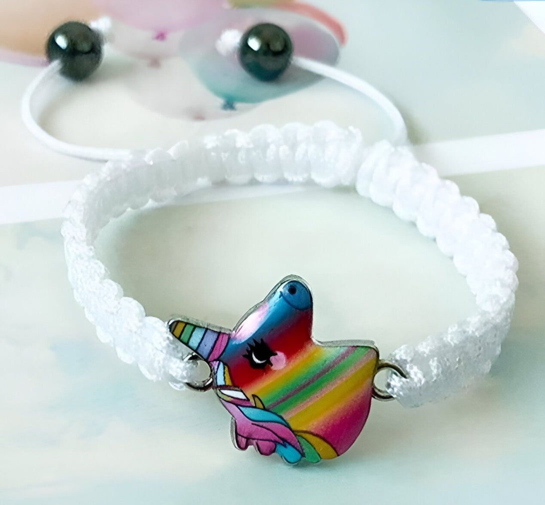 Un bracelet en corde blanche avec un pendentif licorne arc-en-ciel. La licorne a une crinière et une queue arc-en-ciel, et un visage souriant. Le bracelet est ajustable et convient à la plupart des tailles de poignet.