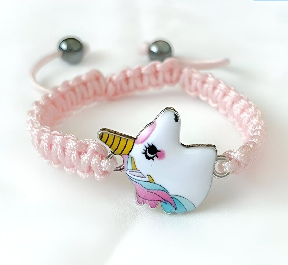 Un bracelet rose avec un pendentif licorne en émail. La licorne est blanche avec une crinière et une queue arc-en-ciel.