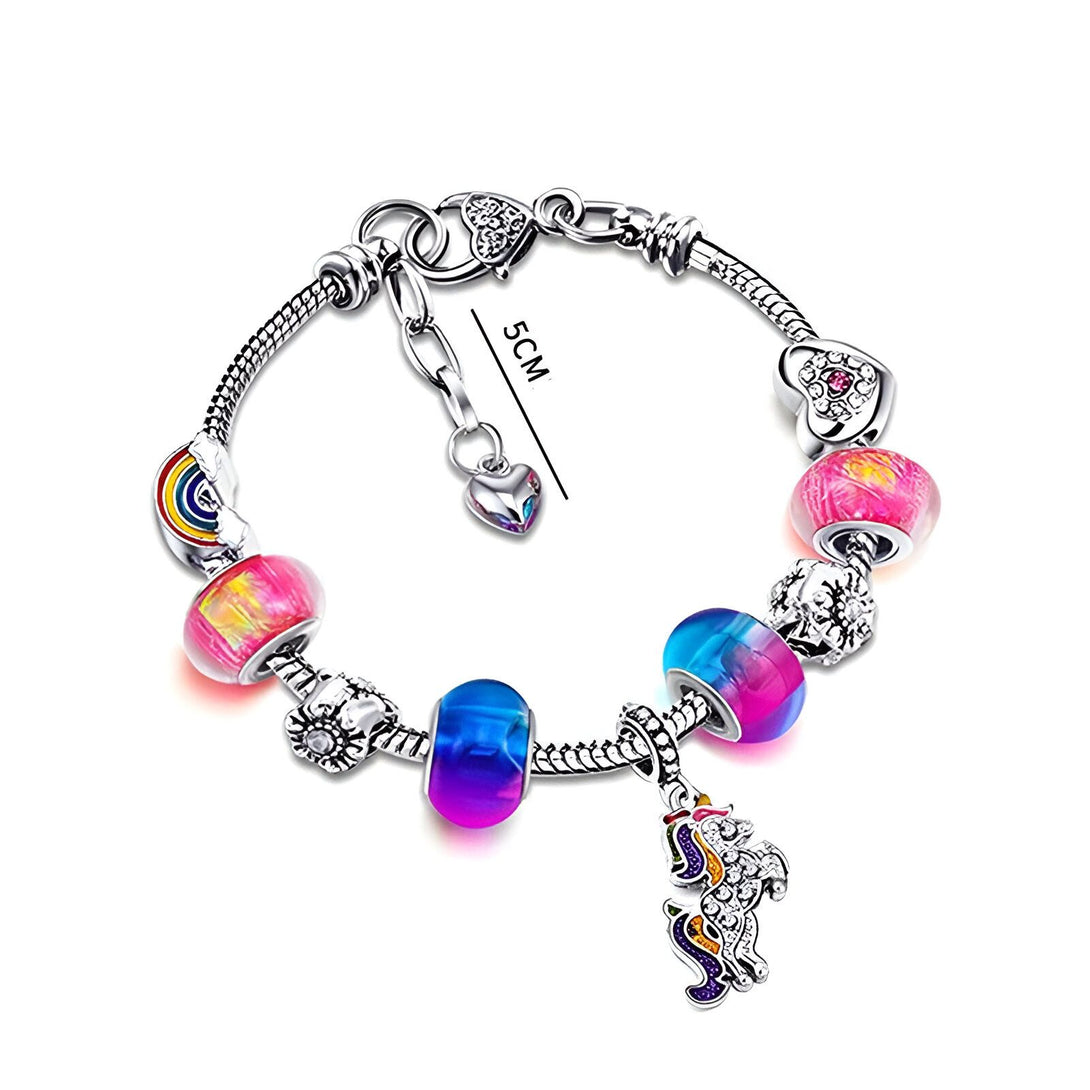 Il s'agit d'un bracelet en argent avec des breloques colorées, notamment un arc-en-ciel, une fleur, un cœur et une licorne.