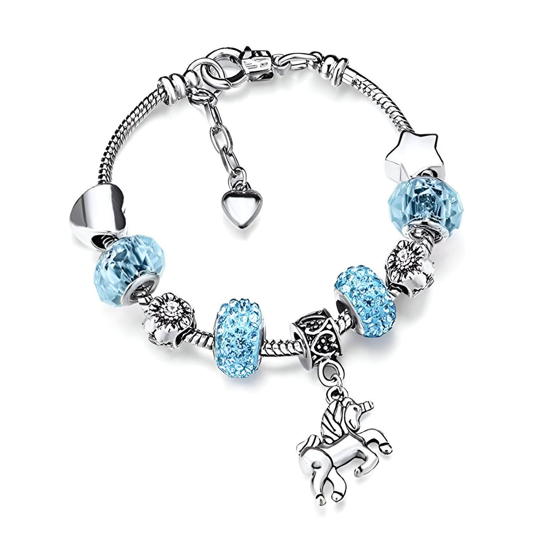 Un bracelet avec des breloques en forme de cœur, de fleur, d'étoile et de licorne. Les breloques sont en cristal bleu clair et le bracelet est en argent.