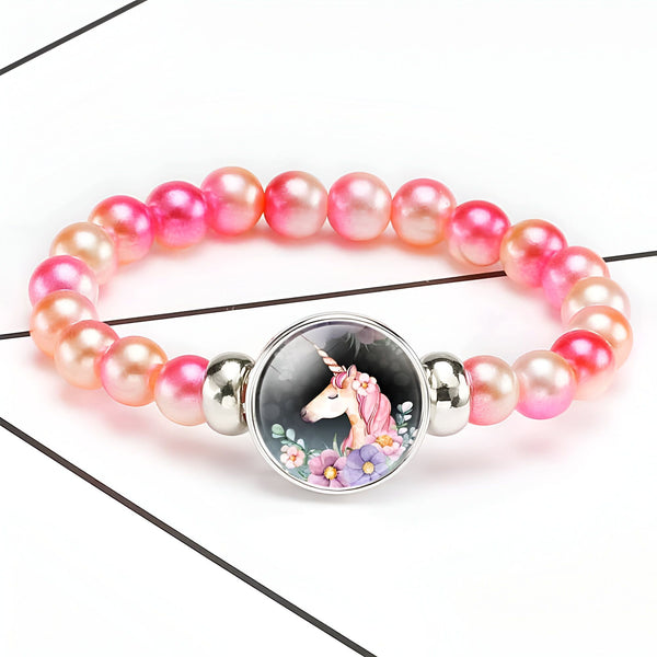 Bracelet de perles roses avec un médaillon licorne. Bijou fantaisie pour enfant avec un pendentif représentant une licorne entourée de fleurs., 45501422600447 | Licorne Shop