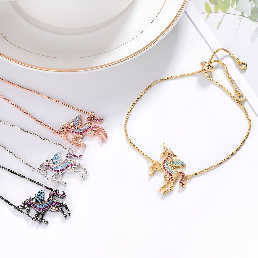 L'image représente un bracelet avec un pendentif en forme de licorne. La licorne est sertie de cristaux de différentes couleurs. Le bracelet est disponible en plusieurs couleurs : doré, argenté, rose gold et noir.