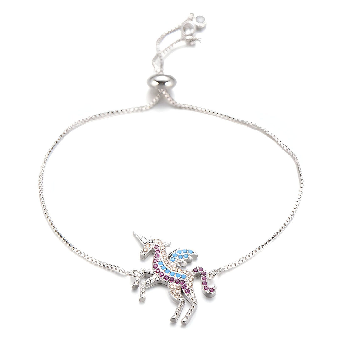 Un bracelet avec une breloque en forme de licorne. La licorne est sertie de cristaux de différentes couleurs. Le bracelet est en argent.