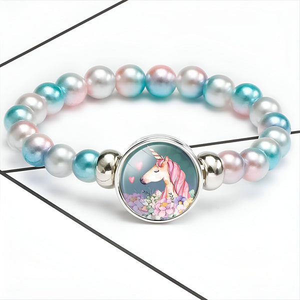Bracelet fantaisie pour enfant. Il a des perles nacrées roses, bleues et blanches, des éléments en métal argenté, et un médaillon avec un dessin de licorne et des coeurs. Bijou mignon pour petites filles., 45501396386047 | Licorne Shop