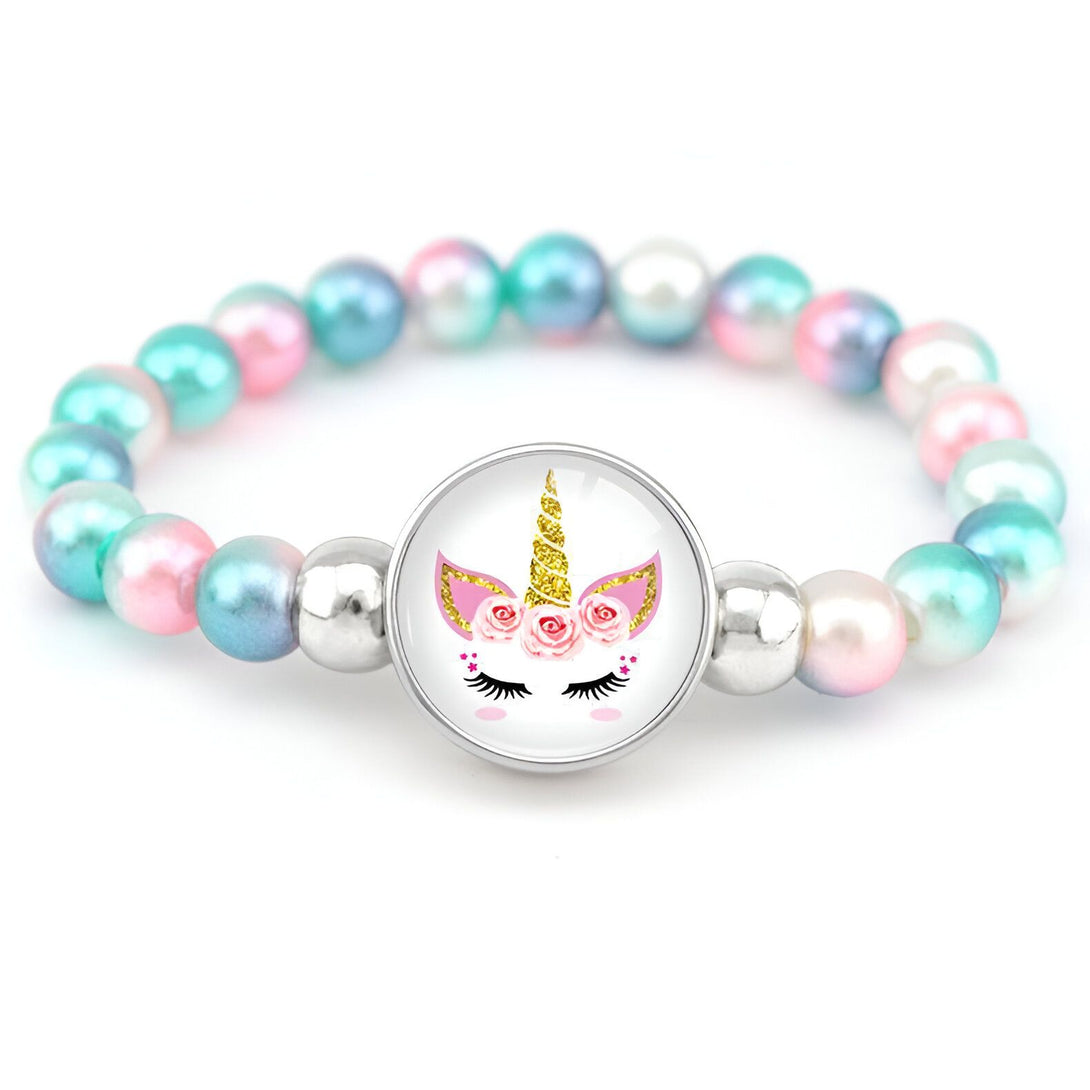 Un bracelet avec des perles roses, bleues et blanches et un pendentif en forme de licorne avec des fleurs dans les cheveux.