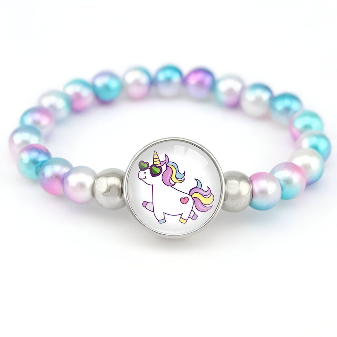 Un bracelet avec des perles roses, bleues et blanches et un pendentif en forme de licorne avec des lunettes de soleil et un cœur sur la cuisse.