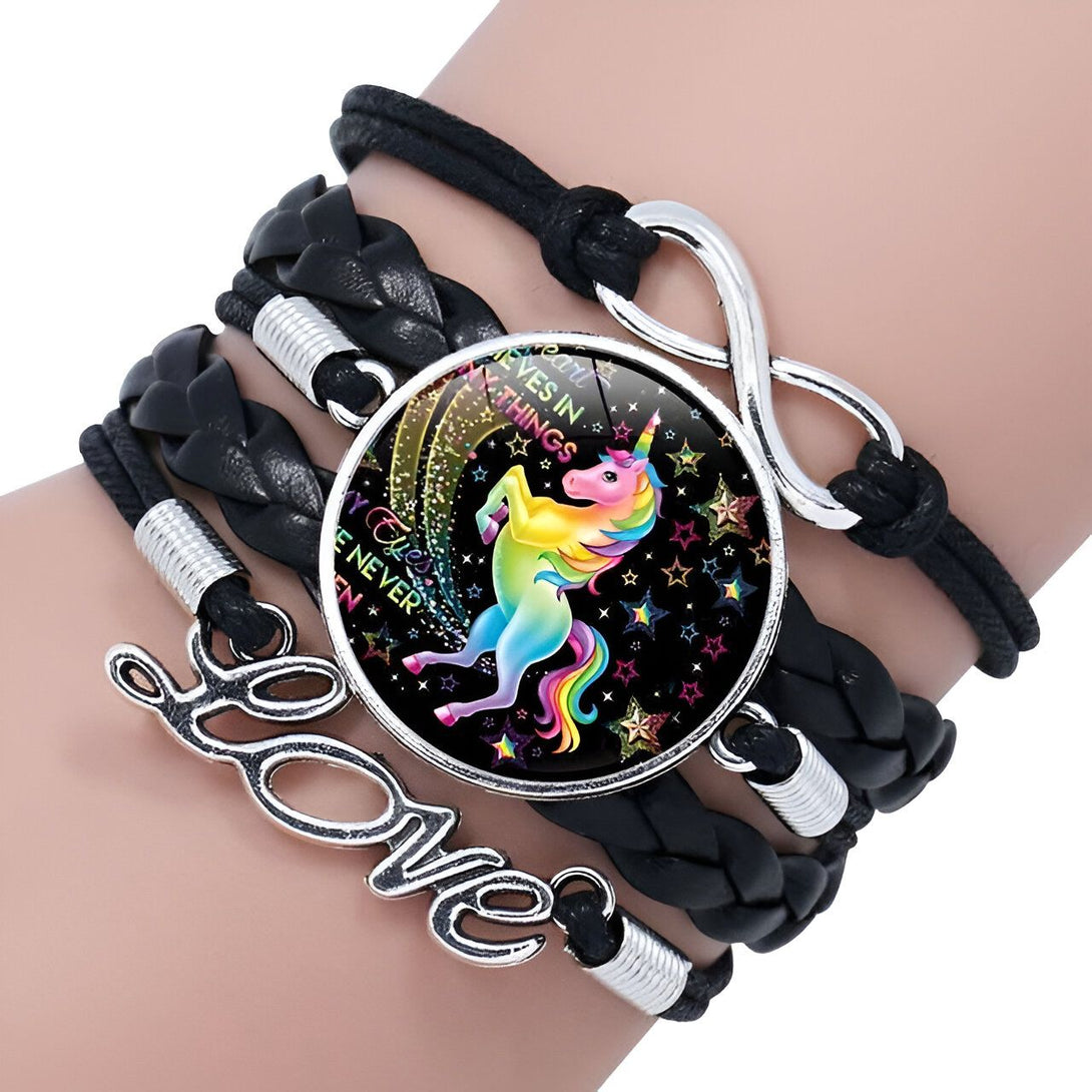 Le bracelet est en cuir noir et comporte une breloque en forme de licorne. La licorne est représentée avec une crinière et une queue arc-en-ciel. Le bracelet est également orné de étoiles et de lunes.