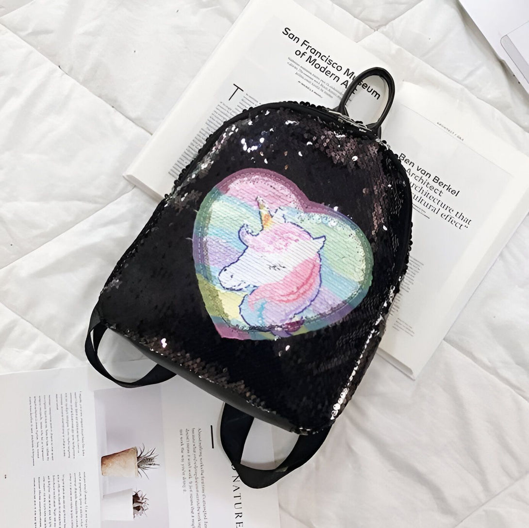 Un sac à dos noir à sequins avec un motif de licorne arc-en-ciel.