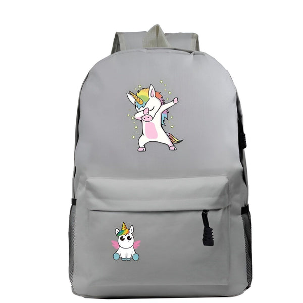 L'image représente un sac à dos gris avec une image de licorne qui fait un dab. La licorne est blanche avec une crinière et une queue arc-en-ciel. Elle porte un collier avec un pendentif en forme de cœur. Le sac à dos a une poche zippée à l'avant et deux poches latérales en filet. Il est parfait pour les enfants ou les adultes qui aiment les licornes.