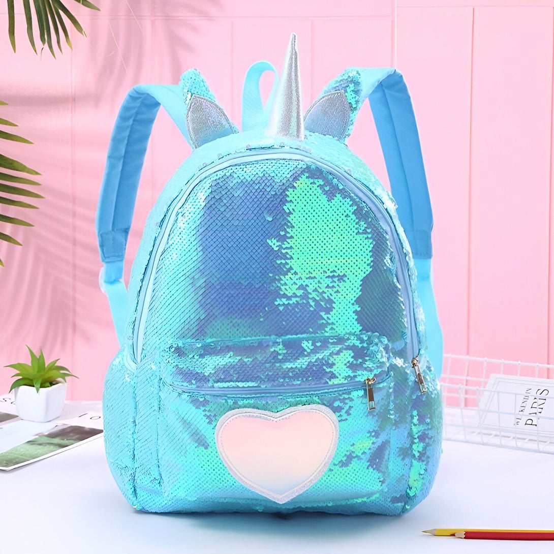 Un sac à dos bleu à paillettes avec une corne de licorne et un cœur rose.