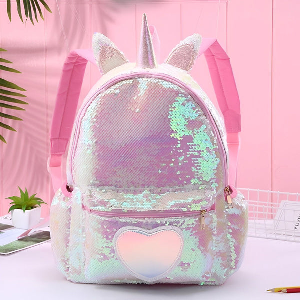 Un sac à dos rose à paillettes avec une corne de licorne et des oreilles de lapin. Il y a une poche en forme de cœur sur le devant du sac.