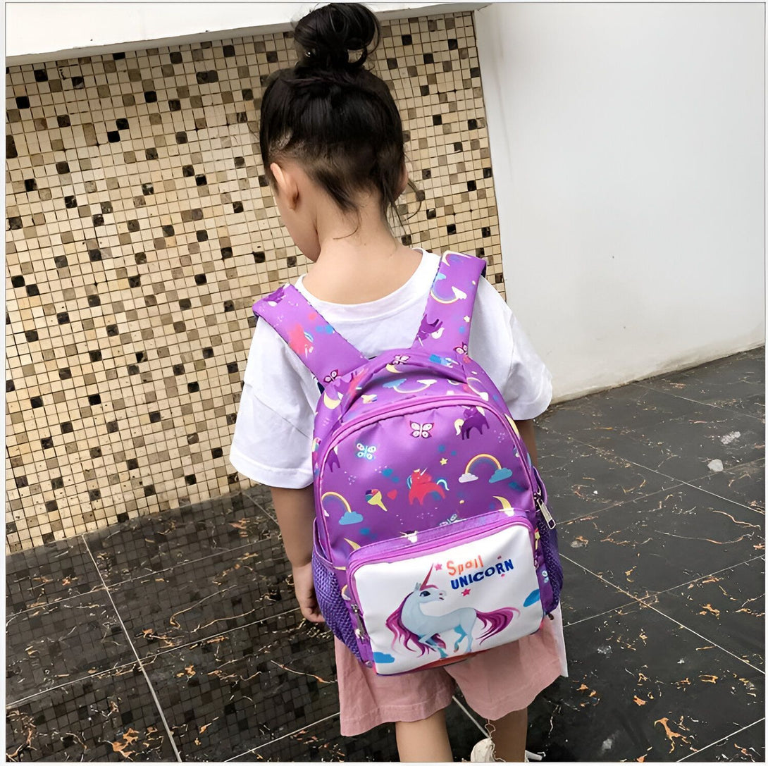 Une petite fille porte un sac à dos violet à l'effigie d'une licorne. Le sac à dos est également décoré de papillons et de fleurs.