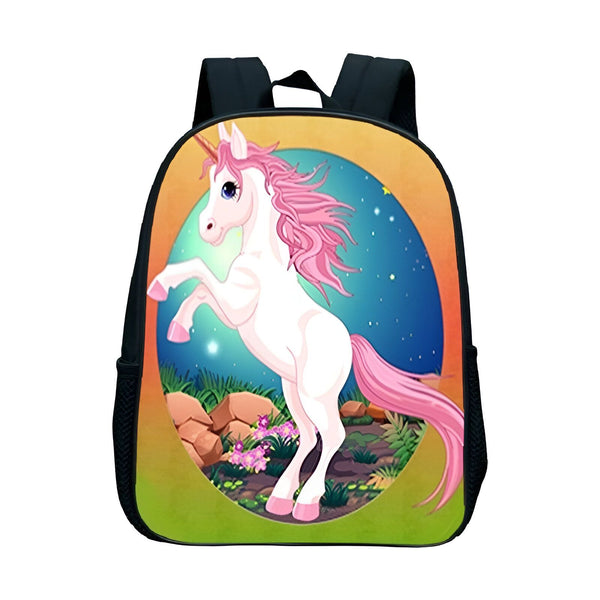 Une image représentant un sac à dos d'écolier avec une illustration d'une licorne blanche avec une crinière et une queue roses. La licorne se tient debout sur ses pattes arrières et se trouve dans un pré vert avec des fleurs et des rochers. Le sac à dos est noir avec des contours blancs et possède deux bretelles noires.