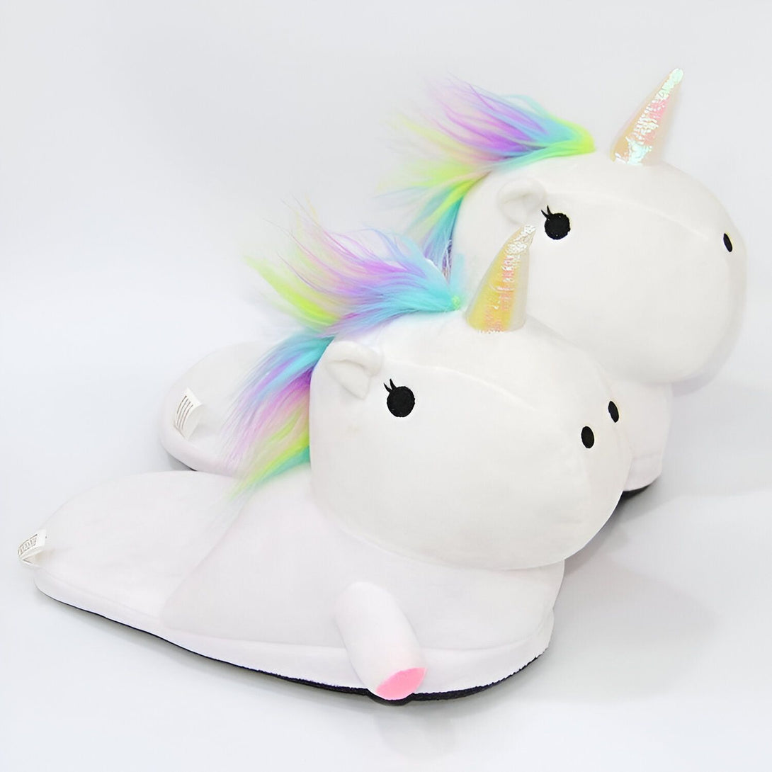 Une paire de pantoufles blanches en forme de licorne avec une crinière et une queue arc-en-ciel.