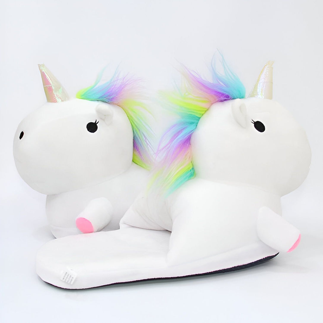 Une paire de pantoufles blanches en forme de licorne avec une corne et une crinière arc-en-ciel.