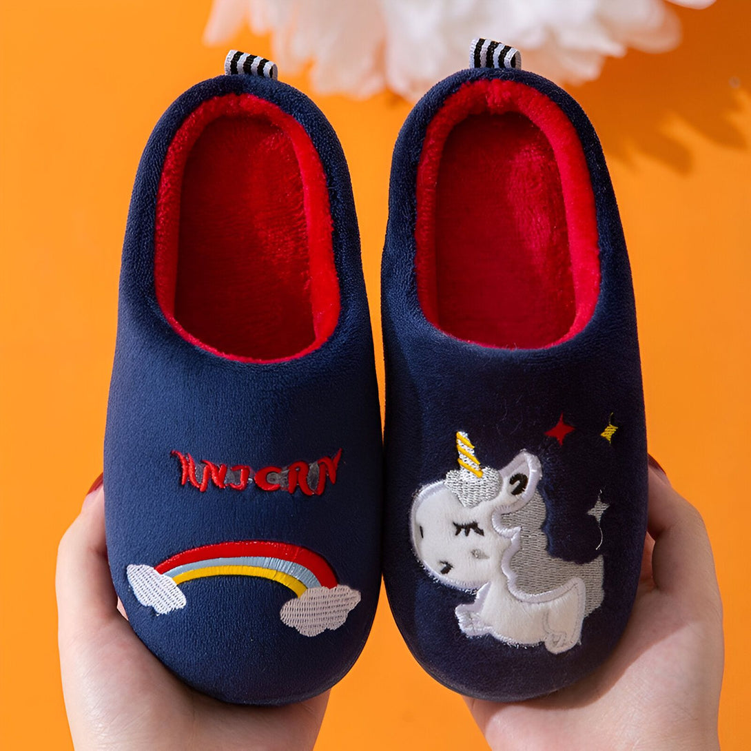 Une paire de pantoufles licorne bleue avec une doublure rouge. Les pantoufles sont brodées d'une licorne blanche et d'un arc-en-ciel coloré.