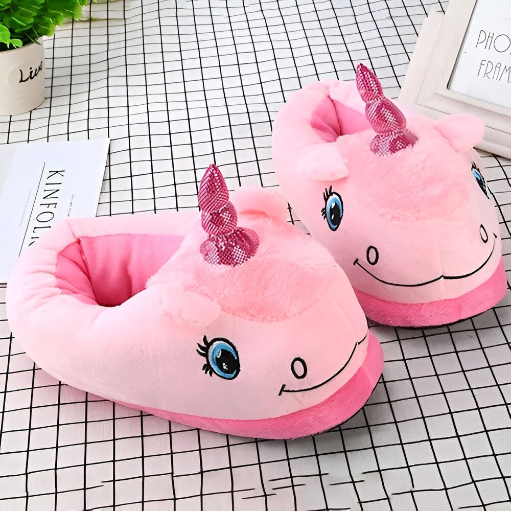 Une paire de pantoufles licorne en peluche rose avec une corne et des yeux.