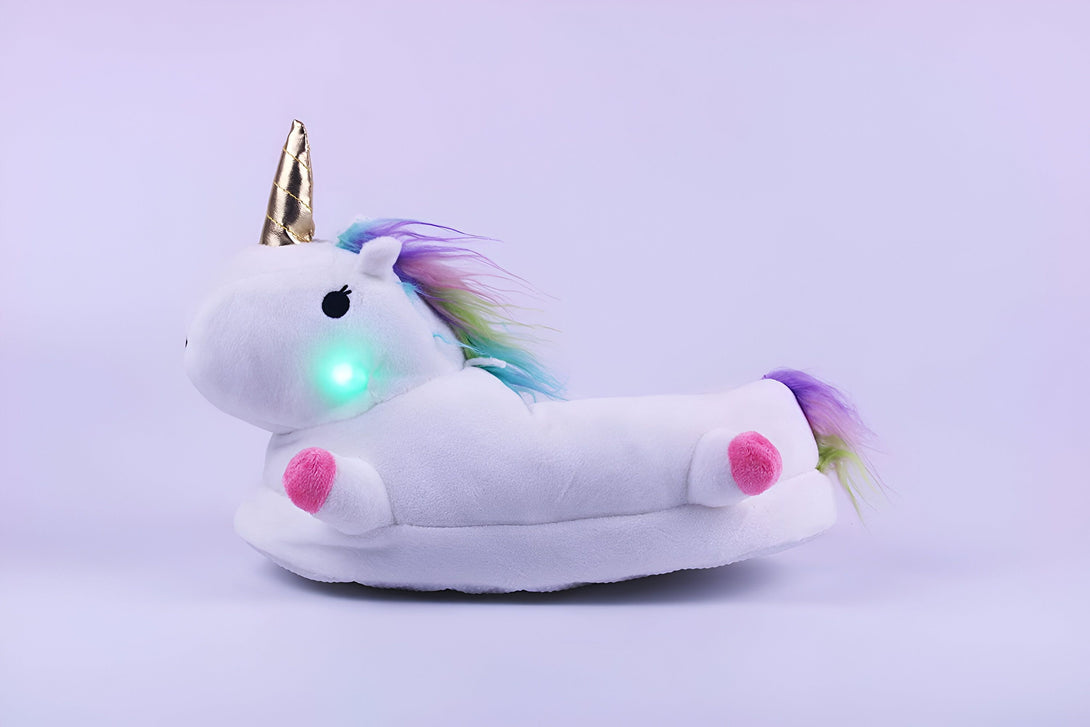 Une peluche licorne blanche avec une corne dorée, une crinière et une queue arc-en-ciel. La peluche est éclairée par une lumière verte.