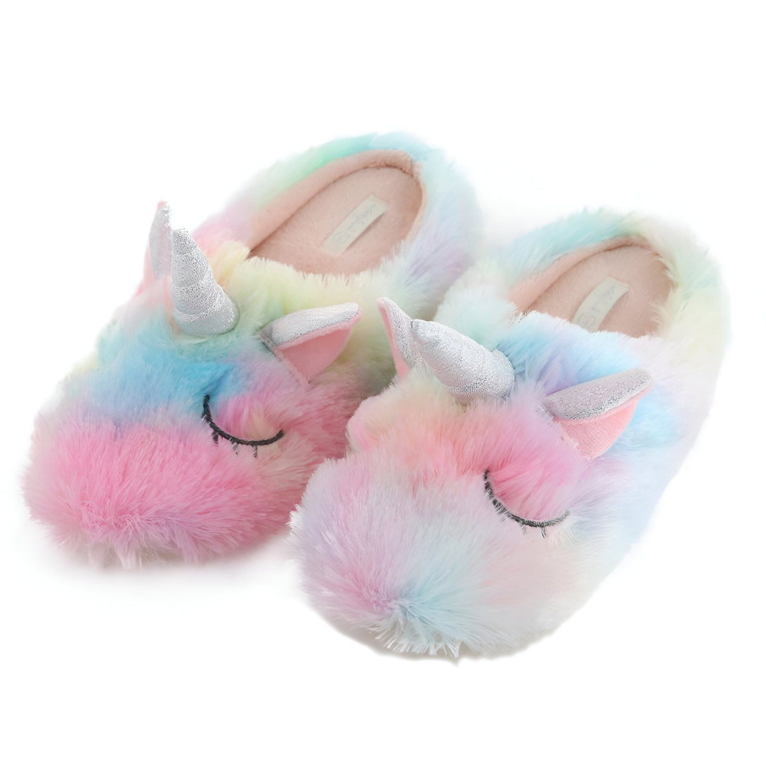Une paire de pantoufles licorne en peluche arc-en-ciel avec une corne et des oreilles argentées. Les pantoufles sont fermées et ont une semelle antidérapante.