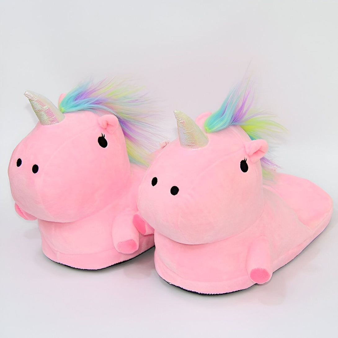 Une paire de pantoufles licorne en peluche rose avec une corne et une crinière arc-en-ciel.