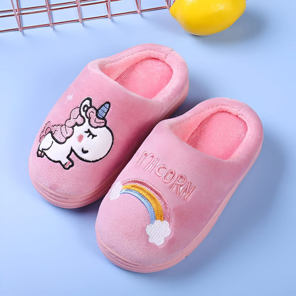 Paire de chaussons roses moelleux avec motifs brodés de licorne et arc-en-ciel, posée sur un fond bleu clair, à côté d'un citron., 45502272110847,45502272143615,45502272176383,45502272209151,45502272241919,45502272274687,45502272307455,45502272340223,45502272372991 | Licorne Shop