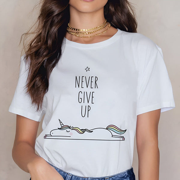 Femme portant un t-shirt blanc avec l'inscription "Never Give Up" et un dessin d'une licorne allongée. Collier doré à plusieurs rangs autour du cou. Cheveux bruns ondulés., 45502313234687,45502313267455,45502313300223,45502313332991,45502313365759,45502313398527,45502313431295,45502313464063 | Licorne Shop