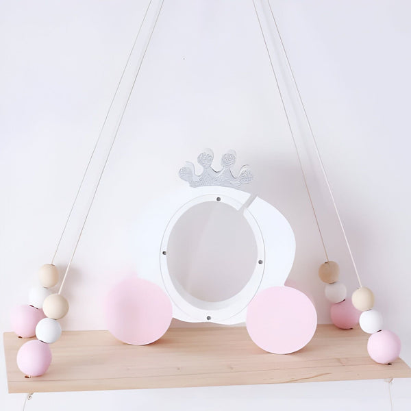 Étagère suspendue pour chambre d'enfant, décorée d'une tirelire blanche en forme de carrosse de princesse avec une couronne pailletée argentée, et des perles roses et en bois clair sur les cordes de suspension., 45501185491199 | Licorne Shop