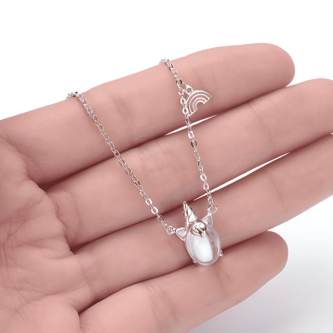 Collier argenté avec pendentif licorne et arc-en-ciel, présenté dans la paume d'une main. Bijou fantaisie élégant et délicat. Accessoire de mode pour femme., 45502392828159 | Licorne Shop