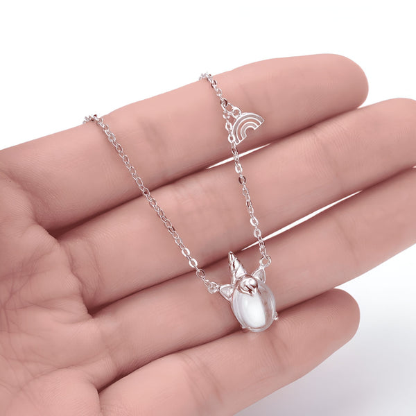 Collier argenté avec pendentif licorne et arc-en-ciel, présenté dans la paume d'une main. Bijou fantaisie élégant et délicat. Accessoire de mode pour femme., 45502392828159 | Licorne Shop