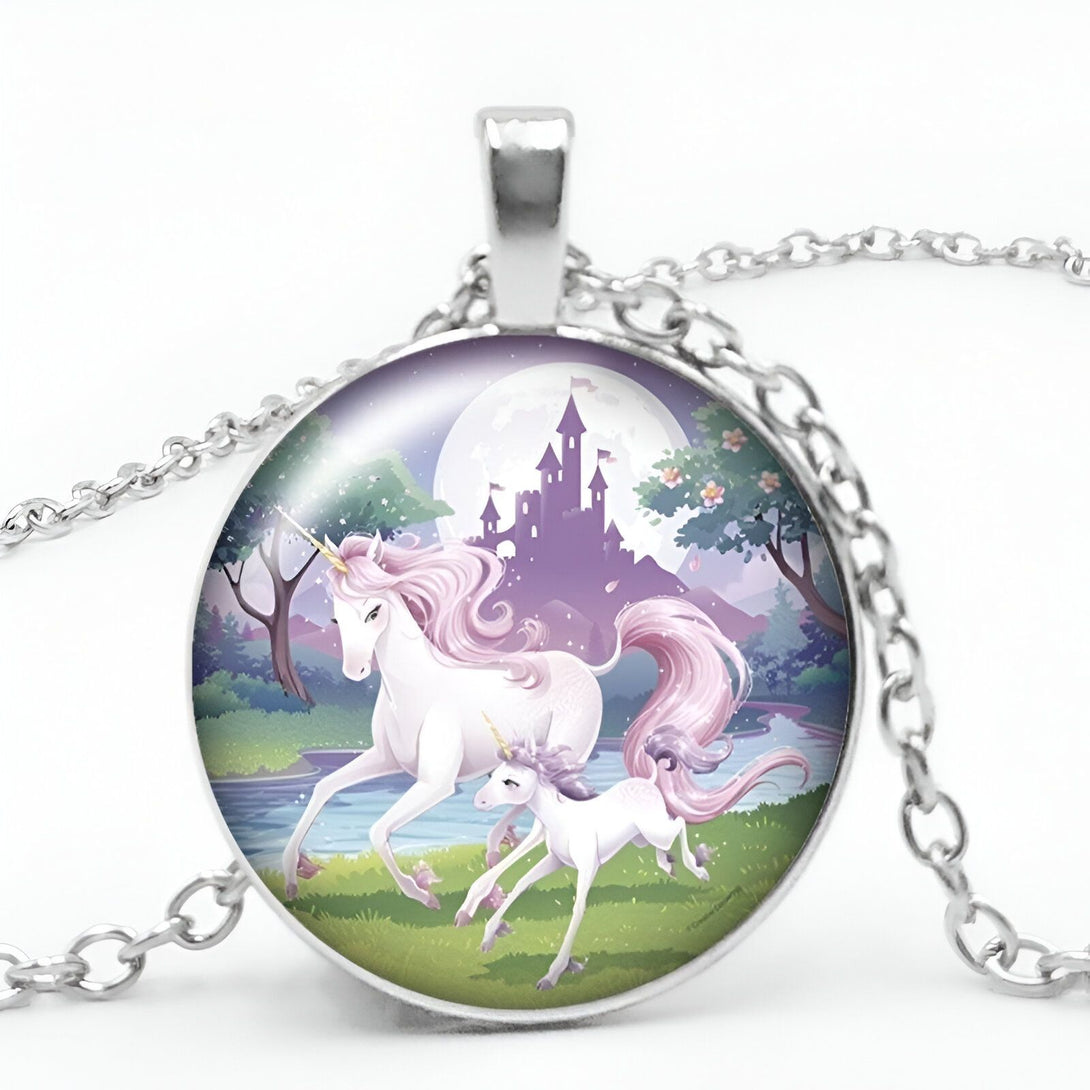 Un pendentif rond en argent avec une image d'une licorne et de son petit. La licorne est blanche avec une crinière et une queue roses. Le petit est blanc avec une crinière et une queue violettes. Ils sont tous les deux dans une forêt verte avec un château en arrière-plan. La lune est pleine et violette.