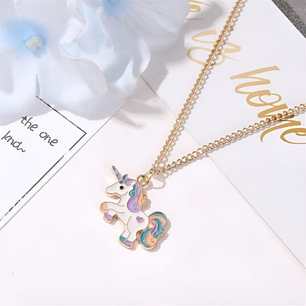 L'image représente un collier avec un pendentif en forme de licorne. La licorne est blanche avec une crinière et une queue arc-en-ciel. Le collier est en métal doré.