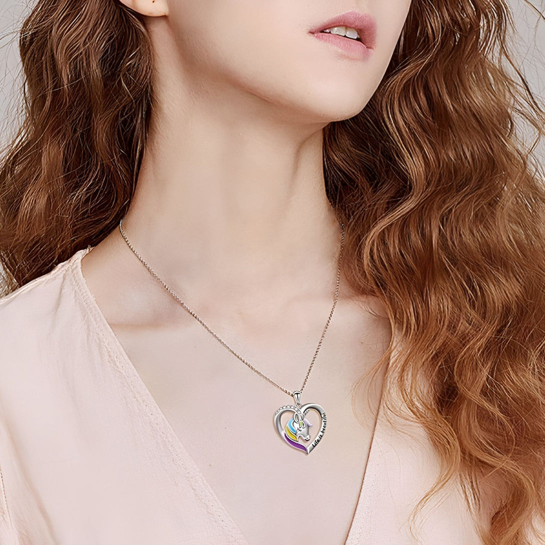 Un collier avec un pendentif en forme de cœur. Le cœur est coloré et contient une silhouette de licorne.