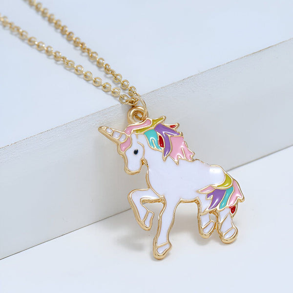 Un collier avec un pendentif en forme de licorne. La licorne est blanche avec une crinière et une queue arc-en-ciel. Le collier est en métal doré.