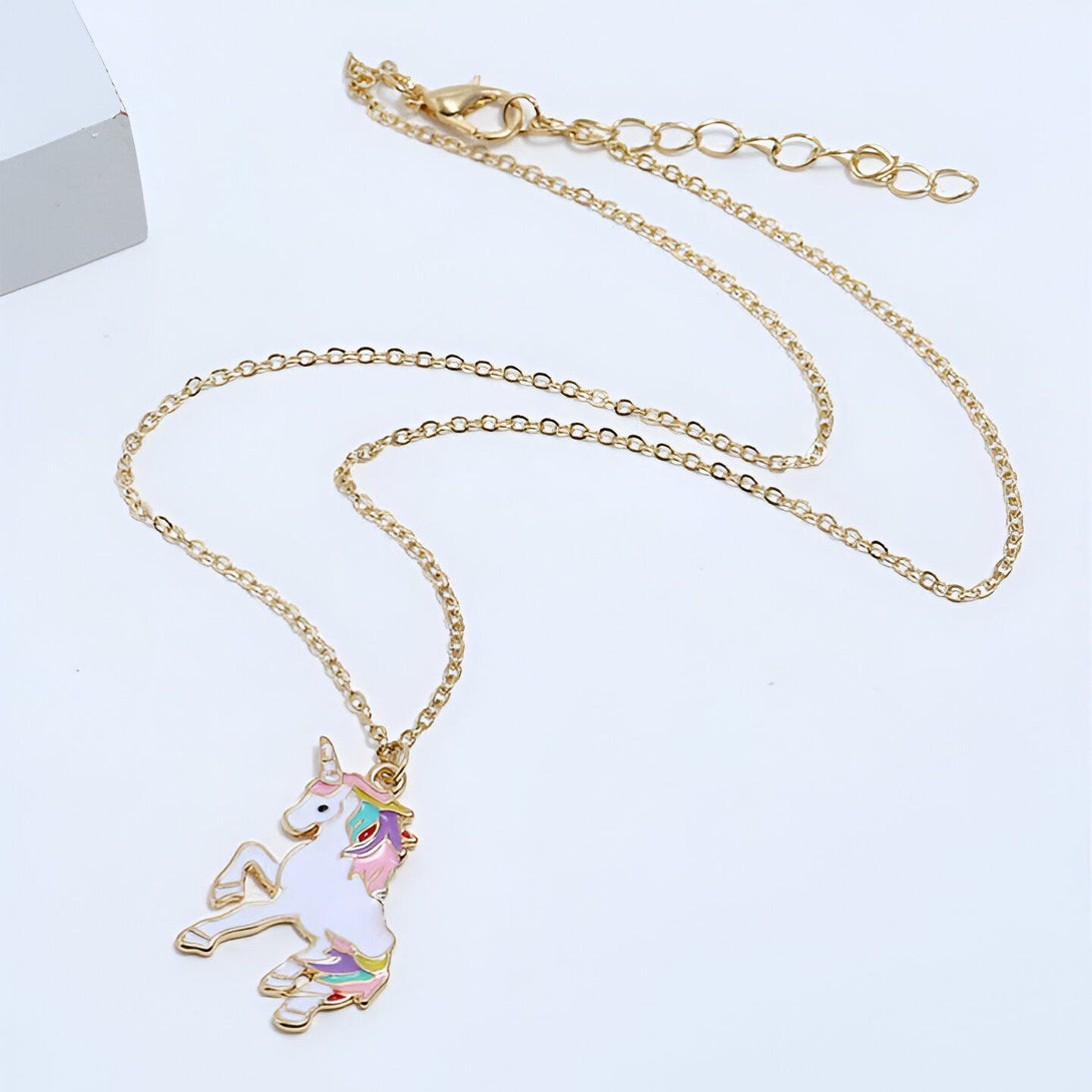 Un collier avec un pendentif licorne en émail coloré. La licorne est blanche avec une crinière et une queue arc-en-ciel. Elle est debout sur ses pattes arrière et a une expression joyeuse sur son visage. Le collier est en métal doré et la chaîne est réglable.